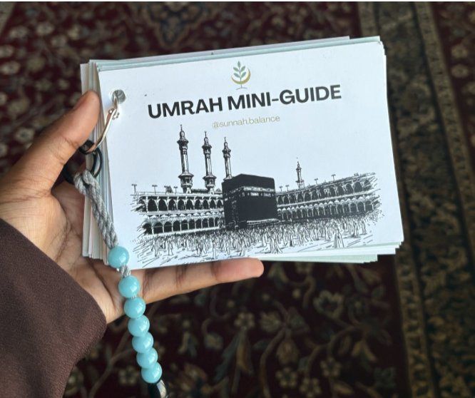 Umrah Mini-Guide booklet held while seated, showing the Sunnah Balance cover