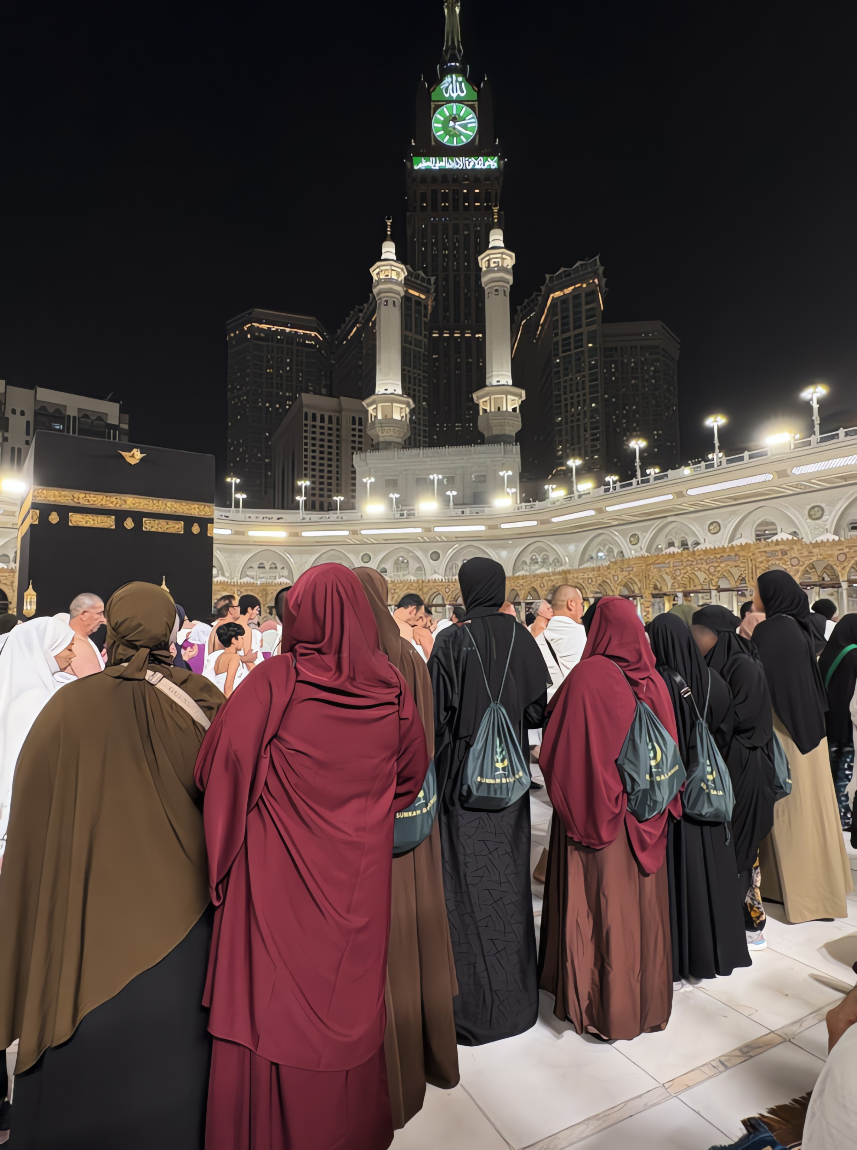 Pilgrims gathered before the Kaaba at night in Makkah, wearing Sunnah Balance drawstring bags