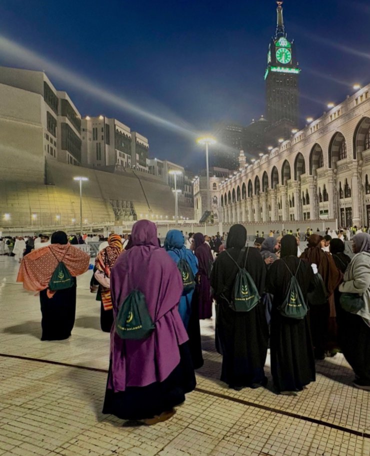 Group at the Masjid al-Haram at night, wearing Sunnah Balance bags, with the Clock Tower behind them